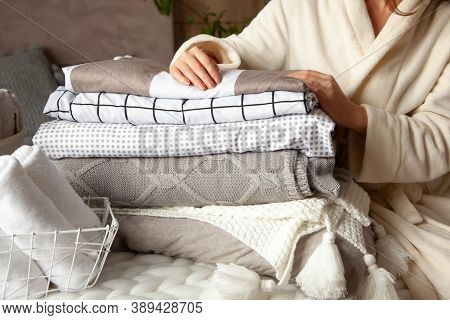 Beautiful Woman In Winter Thick Warm Robe Is Sitting And Neatly Folding Bed Linens And Bath Towels