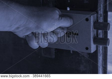 Close-up Of A Man's Hand Locking A Massive Door Lock On A Metal Door. The Inner Part Of The Door Wit