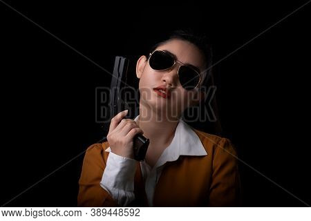 Portrait Beautiful Asia Woman Wearing A Yellow Suit One Hand Holding A Pistol Gun At The Black Backg