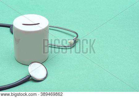 Cost Of Healthcare. Money Box With A Medical Doctors Stethoscope On Green Background. Place For Text