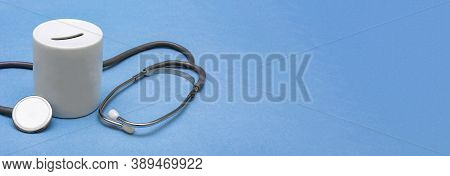 Cost Of Healthcare. Money Box With A Medical Doctors Stethoscope On Blue Background. Place For Text.