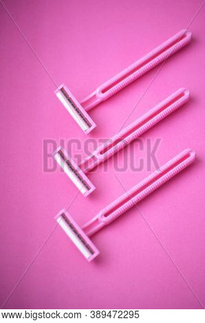 Isolated tree pink plastic female razors for single use on a same pink background. Copy space.