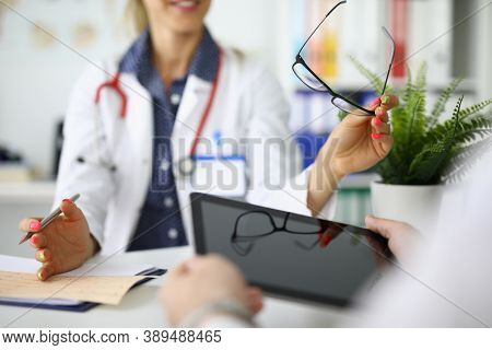 Doctors With Tablet And Glasses In Hands Are Sitting At Table At Meeting In Clinic Closeup. Remote C