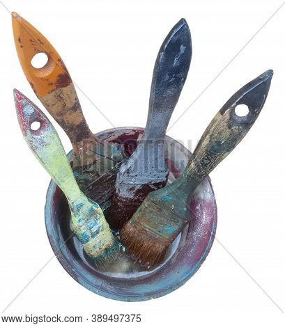 Four Paint Brushes Stained In Paint In A Jar On A White Background