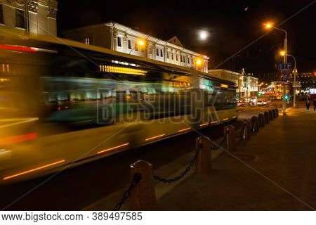 Motion B Lurred Bus Down The Street In The Evening.