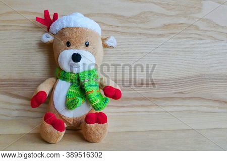 Teddy bear wearing a Christmas hat leaning against a wooden wall for the Christmas celebration