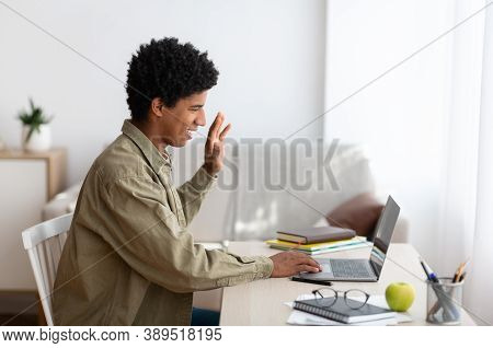Remote Communication Concept. Side View Of Black Teen Guy Speaking To His Teacher Or Fellow Students