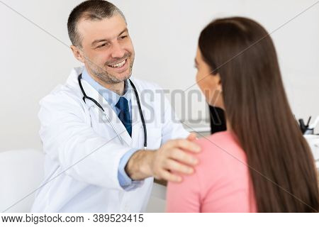 Young Woman At Doctors Appointment. Happy Male Doctor Telling Good News To His Patient, Reassuring, 