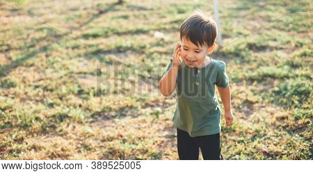 Caucasian Brunette Boy Is Playing Happy In A Field Celebrating Childrens Day In A Sunny Autumn Eveni