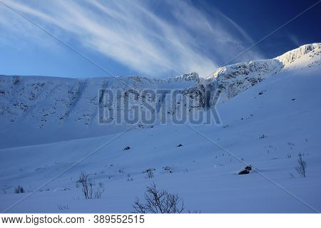 High Snow Covered Rocks Under Clouds On A Winter Day