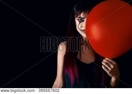 Close Up Portrait Of A Redhead Girl With Evil Clown Makeup, Background Is Black.