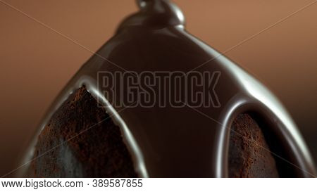Detail of praline with pouring melted chcocolate on top. Studio macro shot.