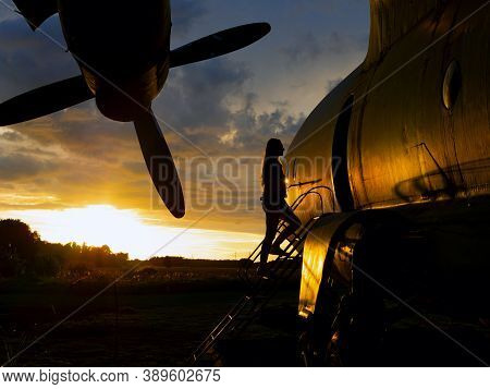 Yo Ungwoman Standing At Plane Ladder Going To Board, Outdoors, Airport. Old Soviet Military Airplane