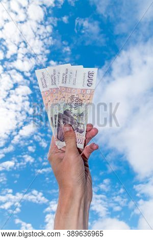 Human Hand Hold 1000 Isk Banknotes. Icelandic Krona Bills On Sky Background.