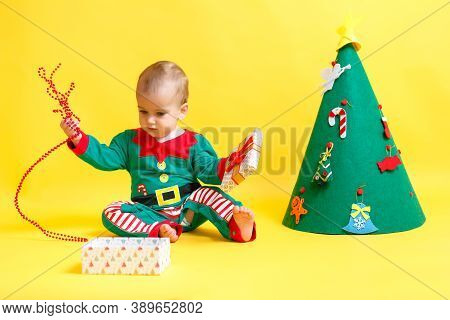Boy In Suit Of Santas Elf Open Gift. Concept Christmas And New Year Holidays