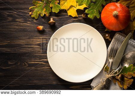 Thanksgiving Food Concept. Autumn Table Setting With Craft Plate, Silverware And Fall Decorations At