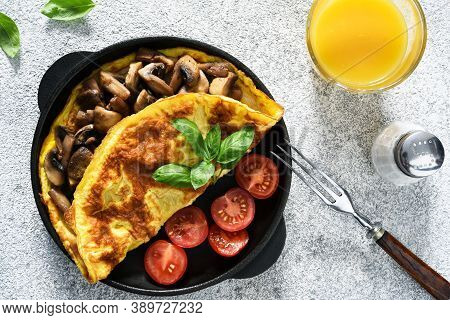 Omelet With Mushrooms And Tomatoes For Breakfast With Orange Sticks On A White Concrete Background.