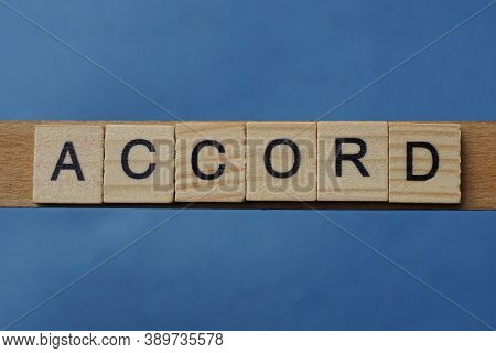 Gray Word Accord In Small Square Wooden Letters With Black Font On A Blue Background