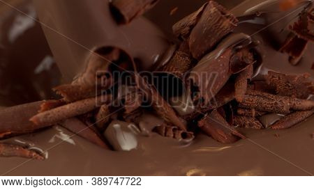 Detail of pouring hot chcocolate with pieces of curls. Studio macro shot.