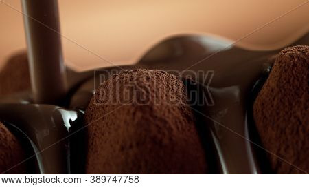 Detail of pralines with pouring melted chcocolate on top. Studio macro shot.