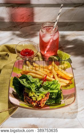 Avocado Chicken Burger Lettuce Wrap With Guacamole And Fries Served With Pink Limeade With Paper Str