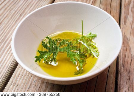 A Citronella Plant Leaf Resting In Oil To Make Homemade Mosquito Repellant