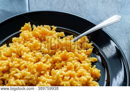 Delicious Spiral Macaroni And Cheddar Cheese On Black Plate