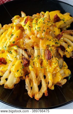 Crispy Waffle Fries Loaded With Bacon And Melted Cheddar Cheese Sauce