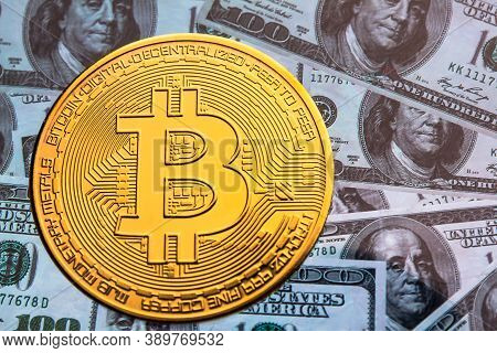 Bitcoin Coin Against The Background Of Us Dollars. A Lot Of American Money Dollars And Gold Bitcoin.