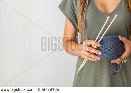 A Young Girl Knitter With Dreadlocks In A Green Dress Holds A Skein Of Blue Yarn And Wooden Knitting
