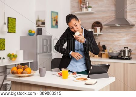 Business Woman Eating Toasted Bread With Butter While Working On Laptop During Breakfast. Concentrat