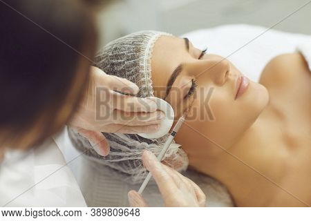 Female Beautician Makes Injections To A Girls Cheekbone To Smooth Facial Wrinkles.