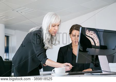Female Boss Affixing Signature On Managers Report. Businesswomen Sitting And Standing At Workplace W