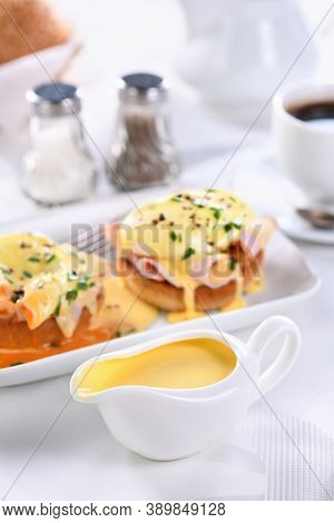 Hollandaise Butter Sauce In A Gravy Boat For Breakfast Served With Eggs Benedict- Fried English Bun,