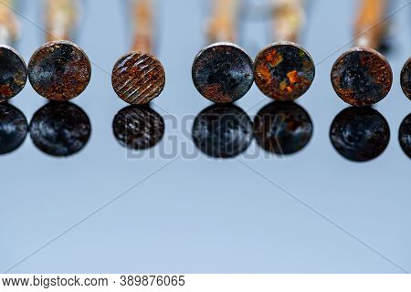 Rusty Used Nails On Light Blue Reflecting Background Close Up Macro Shot, Space For Text.