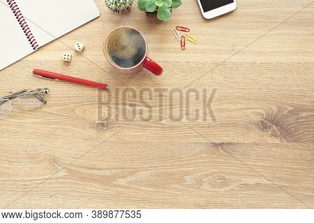 Wooden Office Desk Table With Notebook, Glasses, Plant, Red Cup Of Coffee And Other Office Supplies.