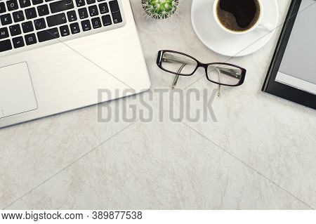Computer, E-book, Glasses, Cactus And A Cup Of Coffee On A Light Marble Table, Background. Top View,
