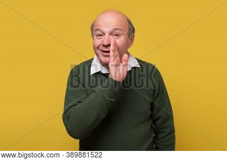 Senior Caucasian Man Whispering A Secret Behind His Hand.