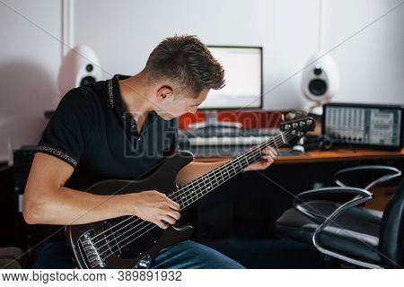 Young Musician Records Bass Guitar Indoors In The Studio.