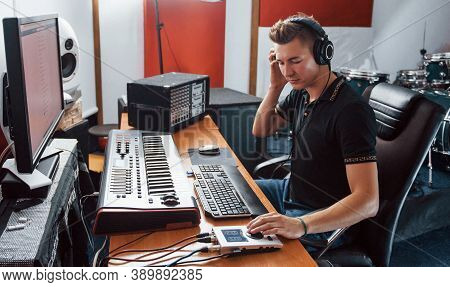 Sound Engineer In Headphones Working And Mixing Music Indoors In The Studio.