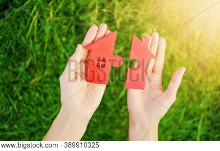 Red House With A Shape Of Two Parts Of Puzzle In Human Hands. Concept Of Apartment Renting, Buying A