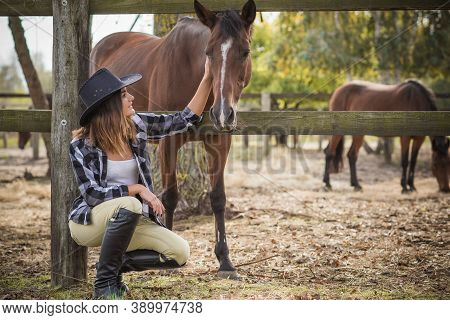 American Woman On A Horse Farm. Portrait Of Girl In Cowboy Hat With A Horses. Hippotherapy At Nature
