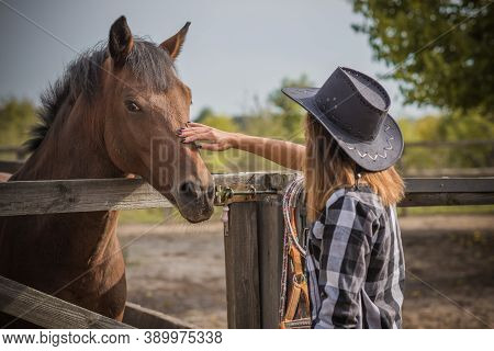 American Woman On A Horse Farm. Portrait Of Girl In Cowboy Hat With A Horses. Hippotherapy At Nature