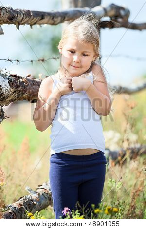 Embarrassed Small Girl Standing In Front Of Rural Fence