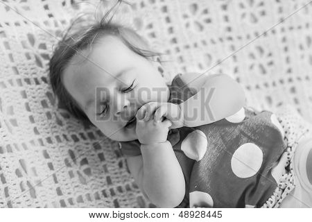 Black And White Photo. Sweet Little Baby Sleeping. She In Blue Dress With White Polka Dots.