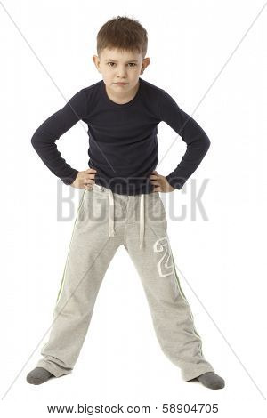 Little boy standing straddle with hands on hip, looking strict. Full size.