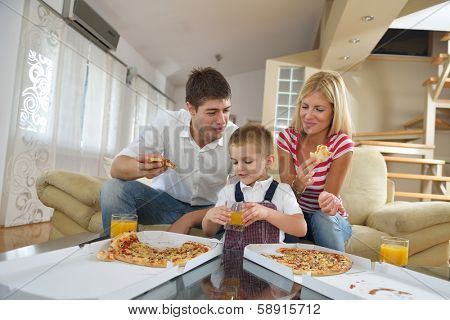 happy young family eating tasty pizza with cheesa and dring healthy and fresh orange juice