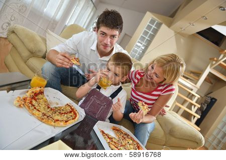 happy young family eating tasty pizza with cheesa and dring healthy and fresh orange juice