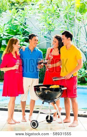 Asian friends having barbecue or BBQ at pool, drinking  wine and celebrating summer time