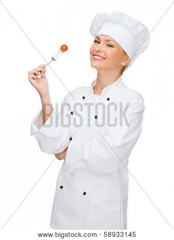 cooking and food concept - smiling female chef, cook or baker with fork and tomato